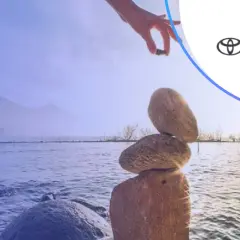 Równowaga jak w toyota bank lokaty. Ręka układa kamienie nad jeziorem.