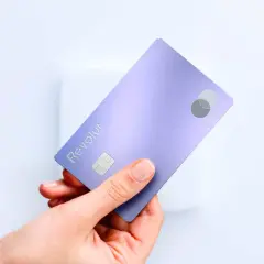 Dłoń trzyma fioletową kartę Revolut, symbol nowoczesnego neo banku. Widoczny chip i logo Mastercard.