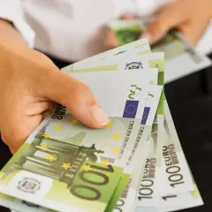 Dłoń trzyma stos banknotów 100 euro. To dobry początek, by pomyśleć o lokacie w euro.