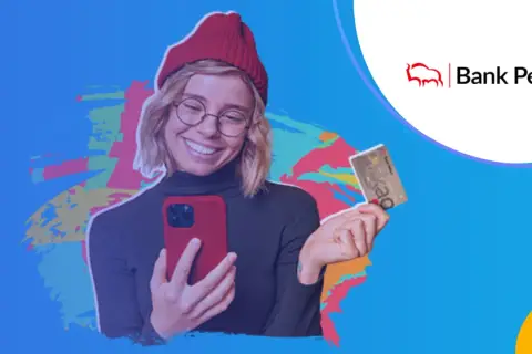Uśmiechnięta młoda kobieta z telefonem i kartą Banku Pekao. Jej konto przekorzystne pekao to klucz do finansowej swobody.