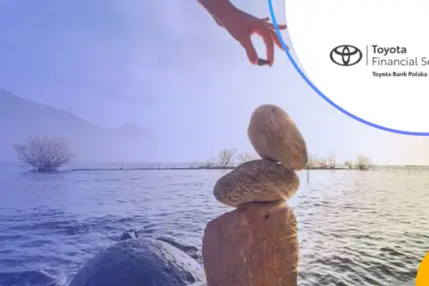 Równowaga jak w toyota bank lokaty. Ręka układa kamienie nad jeziorem.