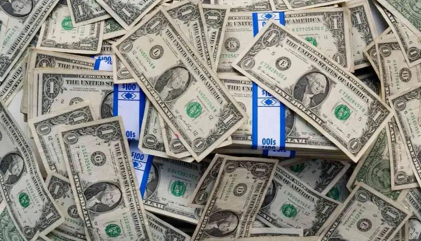 Stosy banknotów jednodolarowych i paczki z napisem "100". To obraz księgowania millenium, gdzie pieniądze odgrywają kluczową rolę.