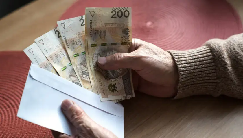 Dłoń trzyma kopertę z banknotami 200 zł. Czy to zaliczka na emerytury 2026?