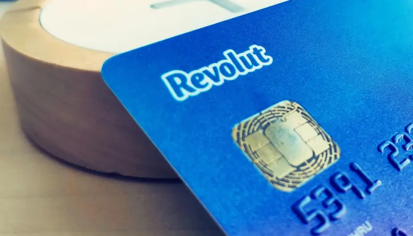 Niebieska karta Revolut z chipem zbliża się do drewnianego elementu. Czy Revolut jest bezpieczny? To pytanie zadaje sobie wielu użytkowników.