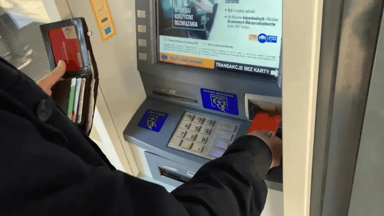 Osoba wkłada kartę do bankomatu, aby dowiedzieć się, jak wypłacić pieniądze z bankomatu.