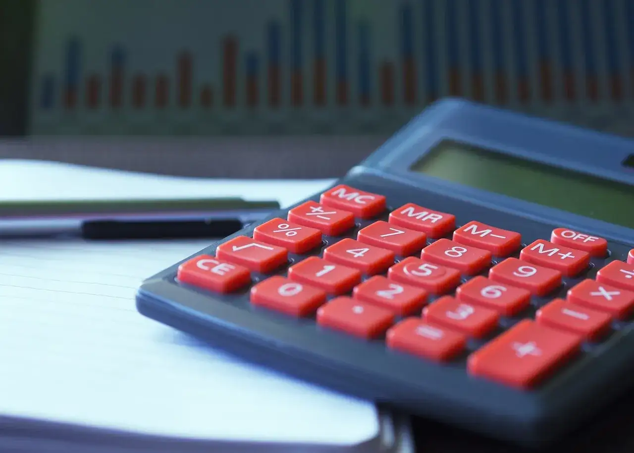 Kalkulator z czerwonymi przyciskami i wykresem w tle. Idealny do zarządzania finansami i planowania rachunku oszczędnościowego.